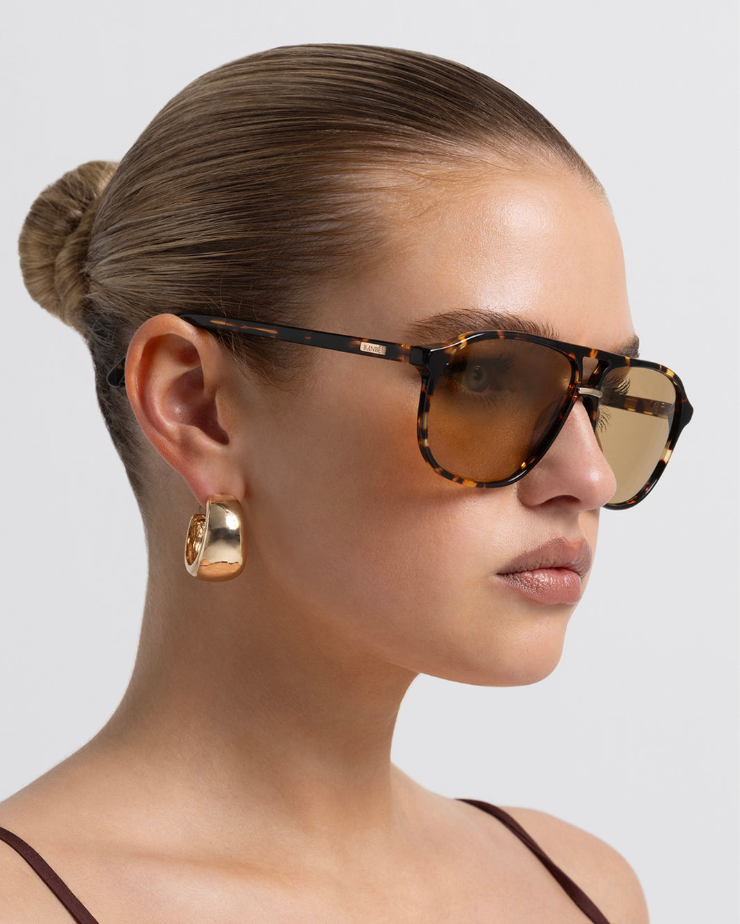 Women's aviator sunglasses in amber tort colourway featuring an oversized modified aviator silhouette with flat-top brow bar, double bridge, angular navigator-inspired shaping, and slim arms for a bold, contemporary look with full coverage.