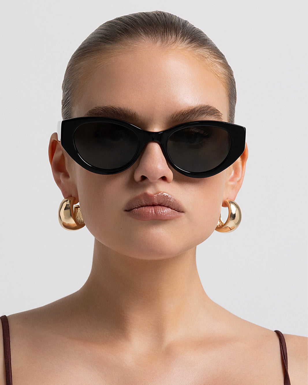 Women’s black cat-eye sunglasses with chunky acetate frame, tinted lenses, front view on model